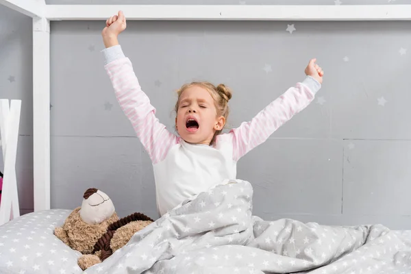 Очаровательный маленький ребенок зевает и растягивается во время пробуждения — стоковое фото