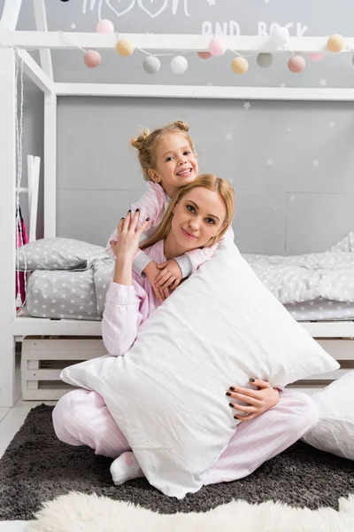Молода красива мати і дочка обіймаються в дитячій спальні — стокове фото