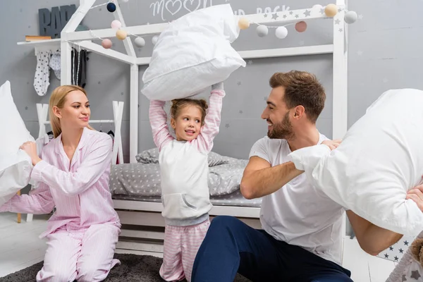 Счастливая молодая семья дралась с подушками в детской спальне — стоковое фото