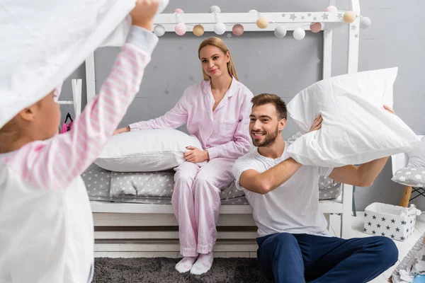 Feliz jovem família lutando com travesseiros no quarto de criança — Fotografia de Stock