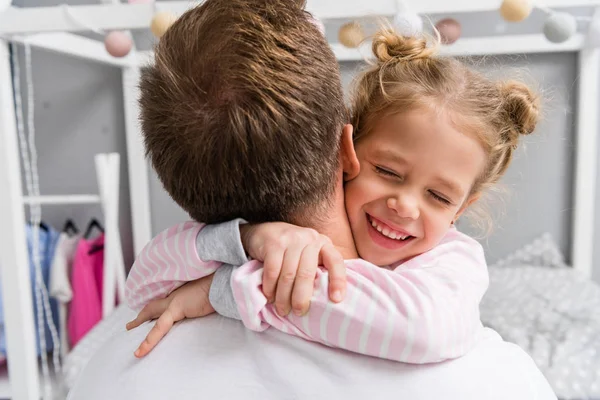 Vue arrière de heureuse petite fille embrassant père — Photo de stock