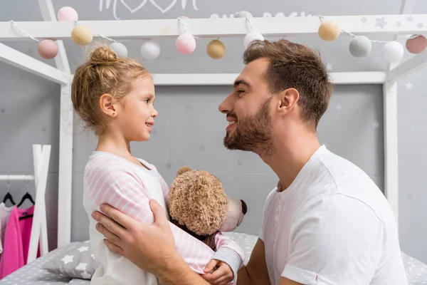 Вид сбоку на молодых отца и дочь в детской спальне — стоковое фото