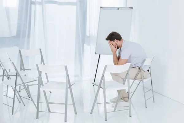 Depressed middle aged man sitting on chair in empty room — Stock Photo