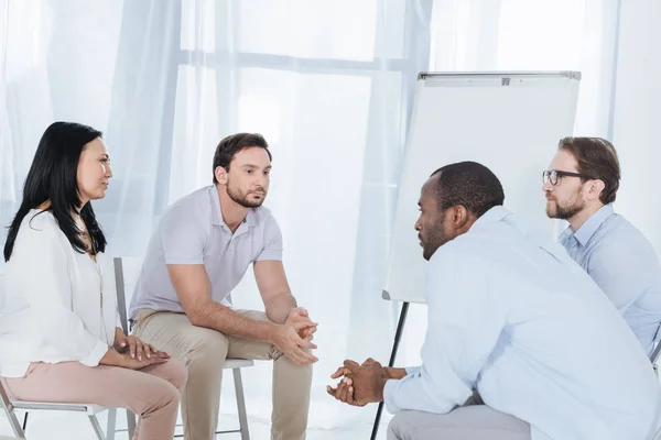 Multiethnic middle aged people sitting on chairs during anonymous group therapy — Stock Photo