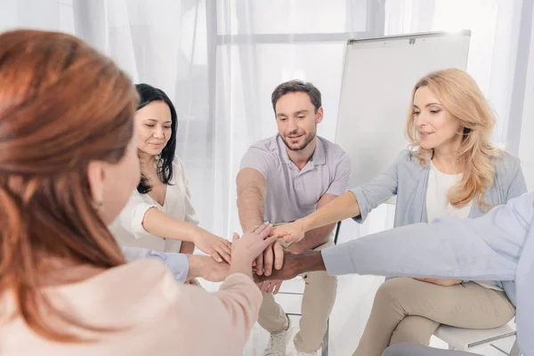 Cropped shot of middle aged multiethnic people stacking hands during group therapy — Stock Photo