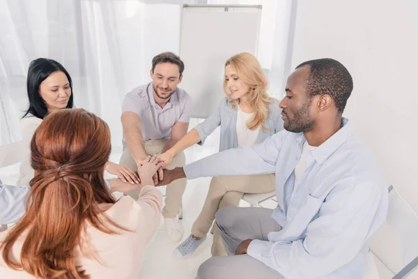 Smiling middle aged multiethnic people stacking hands during group therapy — Stock Photo