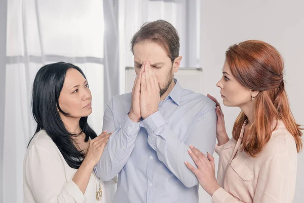 Multiethnic women supporting depressed middle aged man during group therapy — Stock Photo