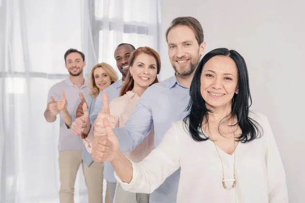 Middle aged people smiling at camera and showing thumbs up during group therapy — Stock Photo