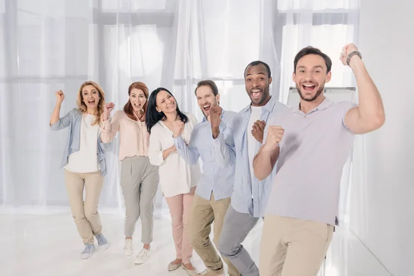 Personas multiétnicas de mediana edad sonriendo a la cámara y triunfando durante la terapia de grupo - foto de stock