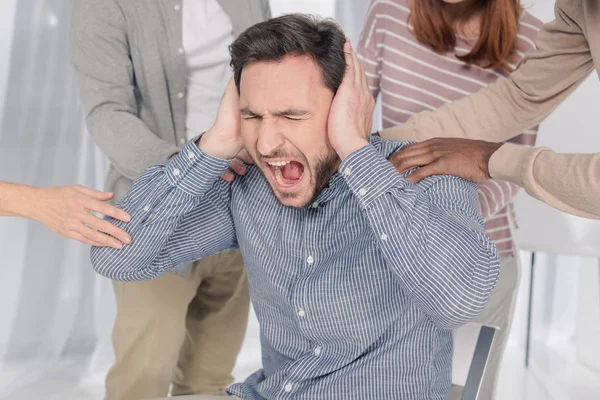 Abgeschnittene Aufnahme von Menschen, die einen depressiven Mann mittleren Alters unterstützen, der während einer Gruppentherapie schreit — Stockfoto