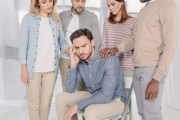 Cropped shot of middle aged multiethnic people supporting upset man during group therapy — Stock Photo