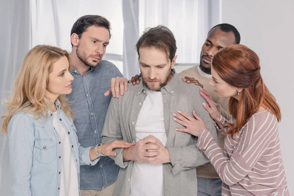 Personnes d'âge moyen multiethniques soutenant l'homme triste pendant la thérapie de groupe — Photo de stock