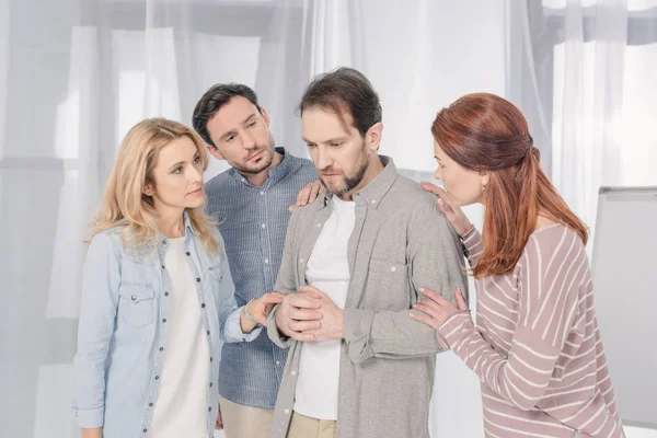 People supporting upset middle aged man during group therapy — Stock Photo