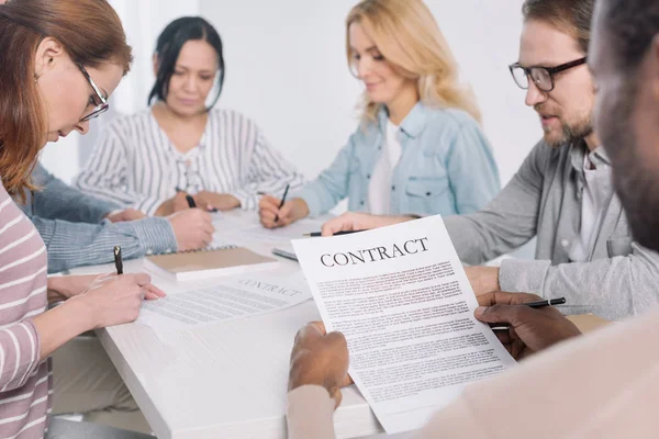 Plan recadré de l'homme afro-américain détenant un contrat et les gens prenant des notes ensemble — Photo de stock