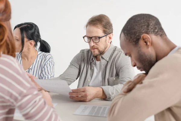 Recortado de cuatro personas de negocios multiétnicos que trabajan con papeles juntos - foto de stock