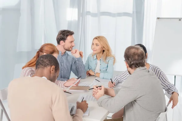 Multiethnic group of people working together and taking notes while having conversation — Stock Photo