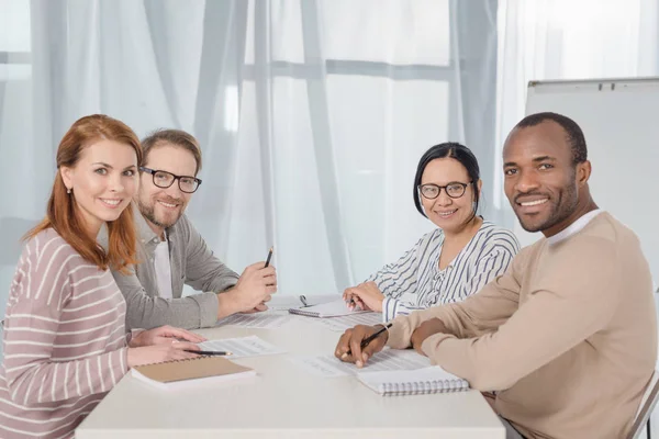 Multiethnic middle aged business people smiling at camera while working together — Stock Photo