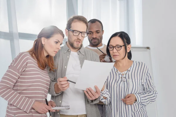 Grupo multiétnico de personas de mediana edad que discuten el documento - foto de stock