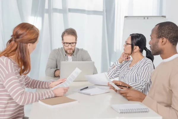 Groupe multiethnique d'âge moyen de personnes utilisant un ordinateur portable et travaillant avec des papiers — Photo de stock