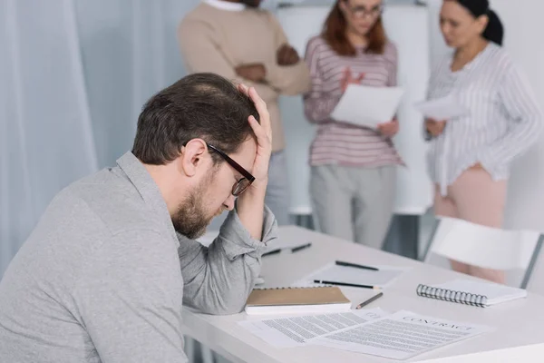 Nahaufnahme eines depressiven Mannes mittleren Alters und Menschen, die hinter ihm stehen — Stockfoto