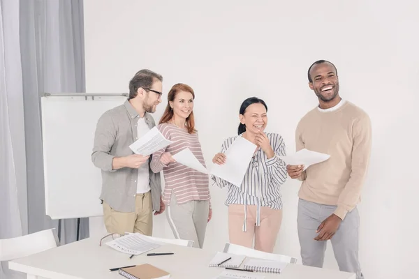 Happy multiethnic middle aged people holding papers and laughing — Stock Photo