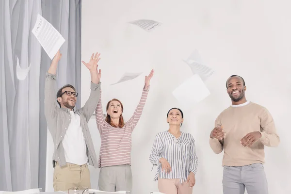 Excited multiethnic middle aged people throwing papers — Stock Photo