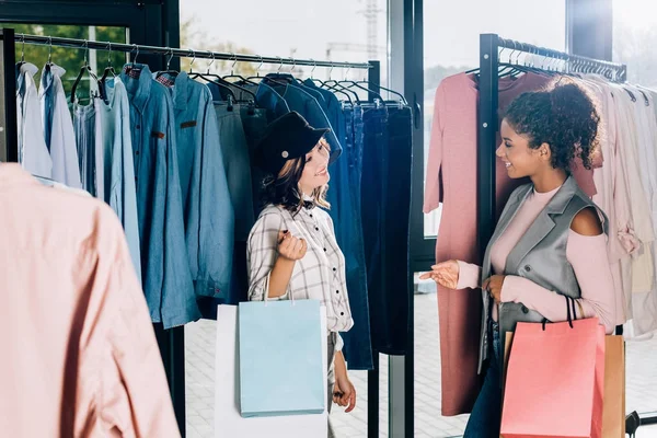 Mujeres jóvenes con estilo con bolsas de compras en la tienda de ropa - foto de stock