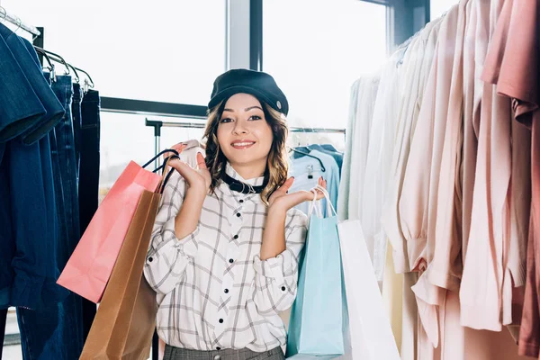 Heureuse belle femme avec des sacs à provisions dans le magasin de vêtements — Photo de stock