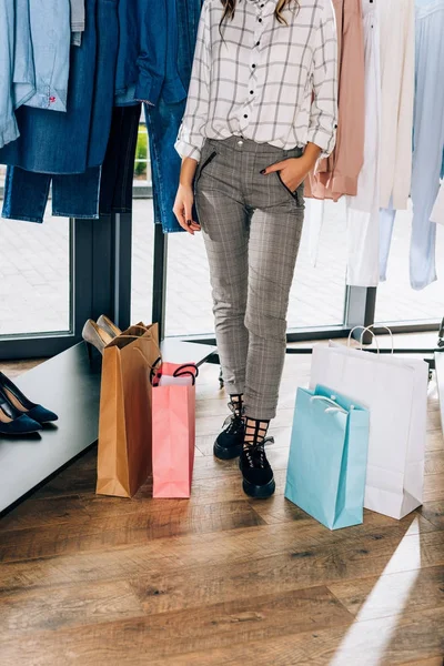 Tiro recortado de mujer con estilo con bolsas de compras en la tienda de ropa - foto de stock