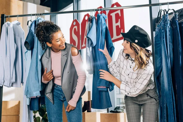 Jóvenes amigos elegantes de compras que se divierten en la tienda de ropa - foto de stock