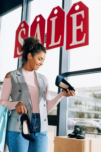 Felice giovane donna in cerca di scarpe al negozio di abbigliamento — Foto stock