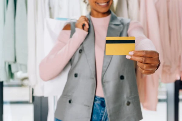 Beautiful young woman showing credit card at clothing store — Stock Photo