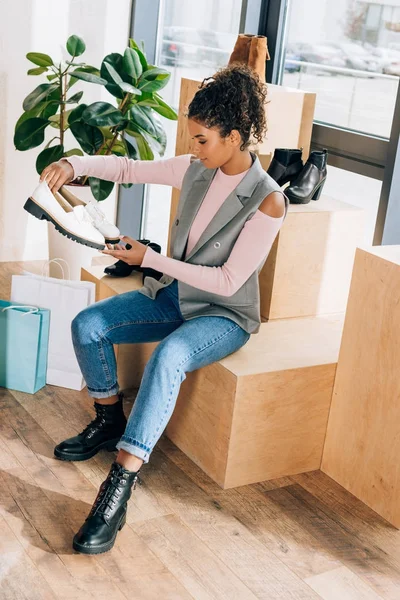 Belle jeune femme à la recherche de chaussures au magasin de vêtements — Photo de stock