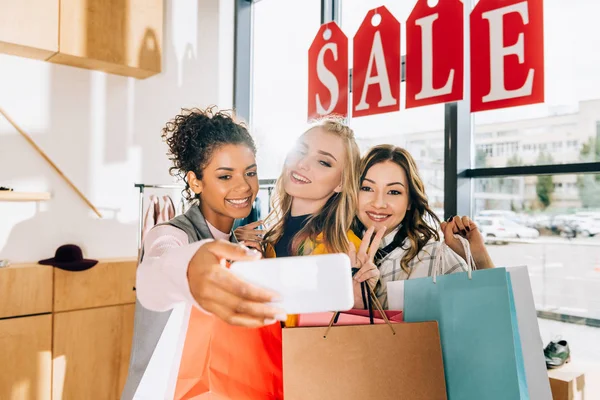 Grupo de mujeres jóvenes felices tomando selfie en las compras - foto de stock