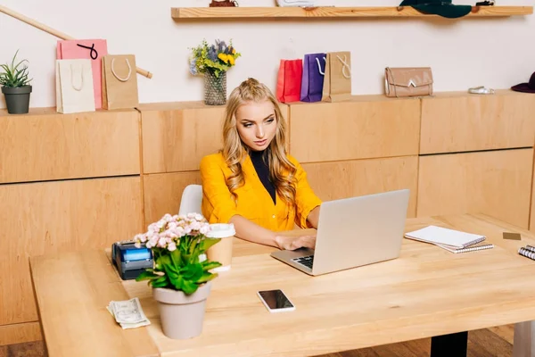 Direttore del negozio di abbigliamento utilizzando laptop sul posto di lavoro — Foto stock