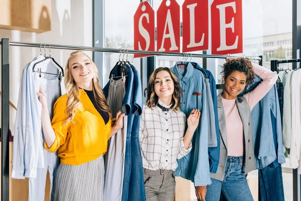 Grupo de mujeres jóvenes multiétnicas en las compras en la tienda de ropa - foto de stock