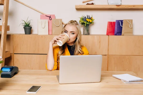 Clothing store manager drinking coffee from disposable cup at workplace — Stock Photo