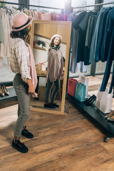 Happy young woman looking at mirror in clothing store — Stock Photo