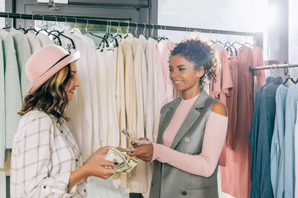 Giovani donne alla moda contando contanti nel negozio di abbigliamento — Foto stock
