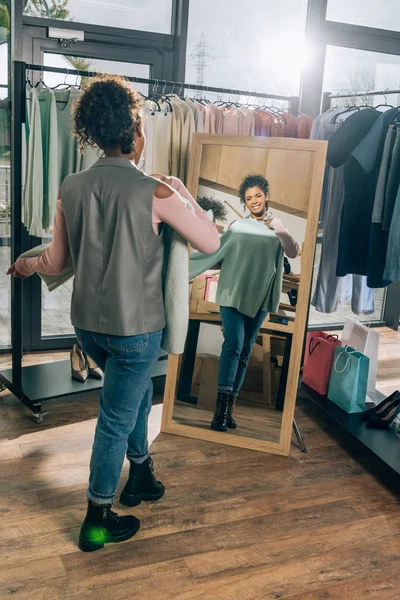 Attraente giovane donna guardando specchio in negozio di abbigliamento — Foto stock