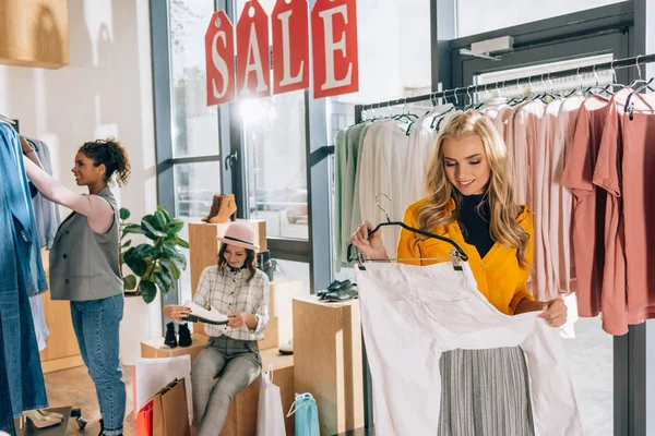 Gruppo di giovani donne a fare shopping in negozio di abbigliamento in vendita — Foto stock