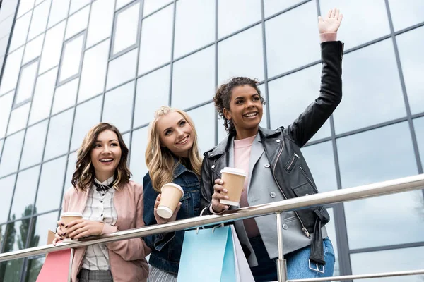 Grupo de mujeres jóvenes en compras con café para salir al aire libre - foto de stock