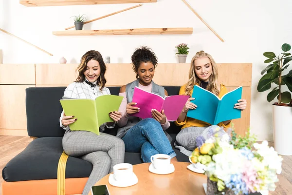 Groupe de jeunes copines de lecture de magazines dans le café — Photo de stock