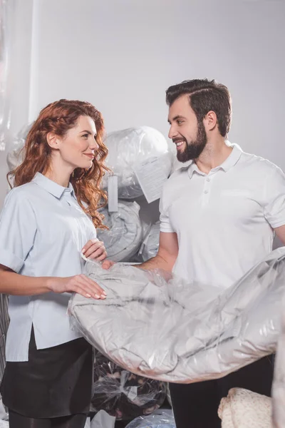 Dry cleaning workers with jacket in bag at warehouse — Stock Photo