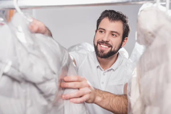 Dry cleaning worker at warehouse with clothing packed in plastic bags — Stock Photo