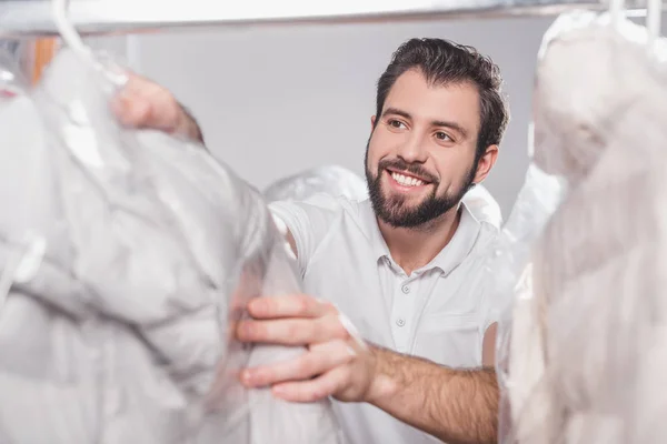 Reinigungskraft im Lager mit in Plastiktüten verpackter Kleidung — Stockfoto