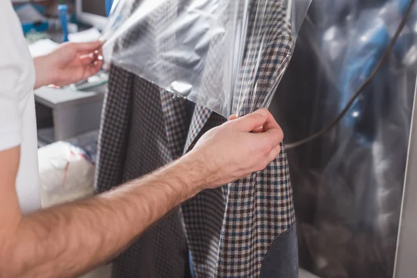 Cropped shot of dry cleaning worker packing jacket in plastic bag — Stock Photo