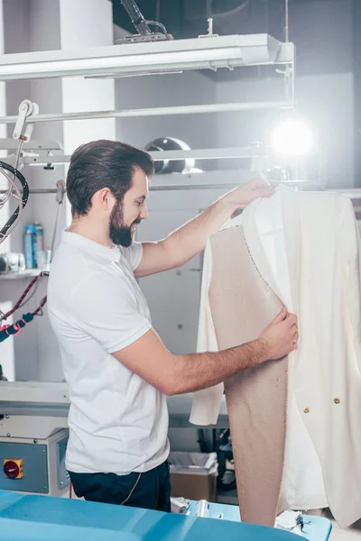 Trabajador de limpieza en seco con chaqueta blanca en percha - foto de stock