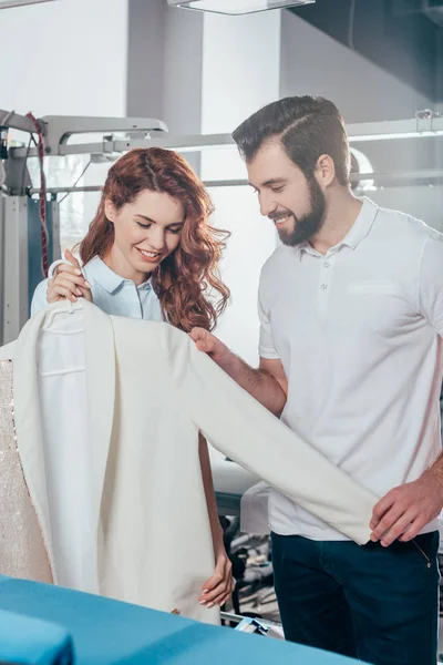 Jeunes travailleurs de nettoyage à sec tenant une veste blanche propre à l'entrepôt — Photo de stock