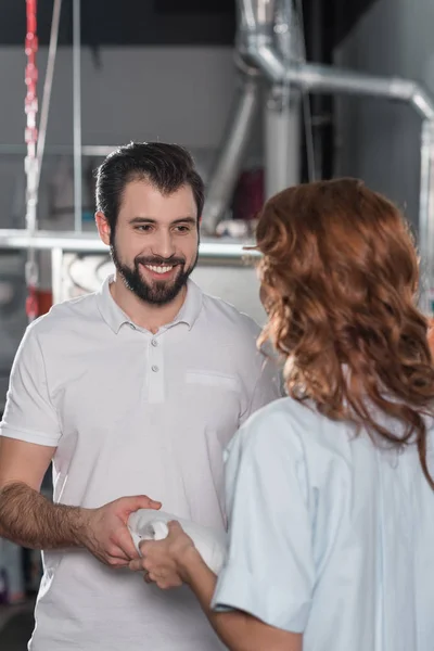 Dry cleaning workers passing clean folded clorhes — Stock Photo